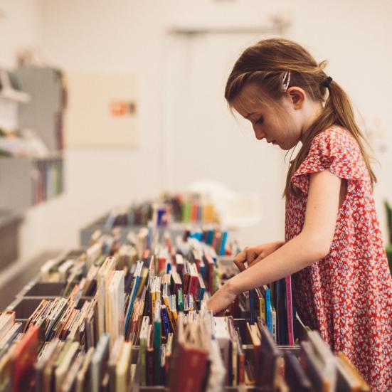 Billede af en pige der bladrer i en kasse med bøger