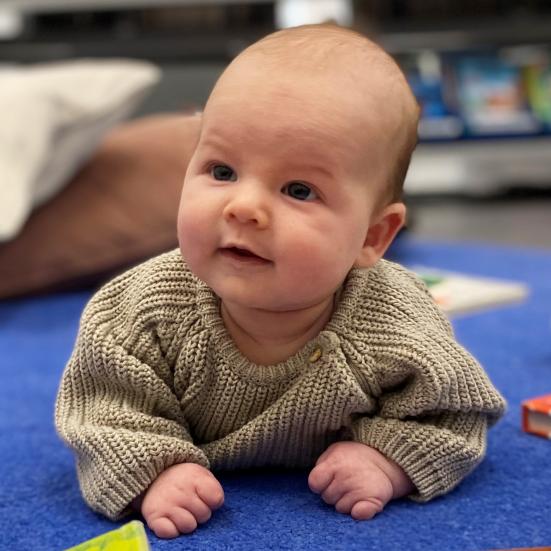 Baby liggende på pude med bøger