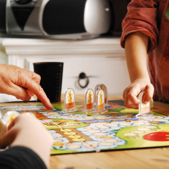 Hænderne af et barn og voksen der spiller brætspil