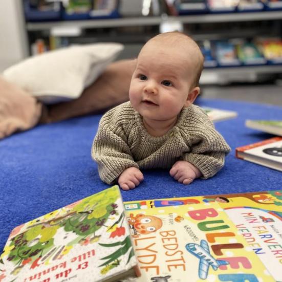 baby ligger på gulv med pegebøger