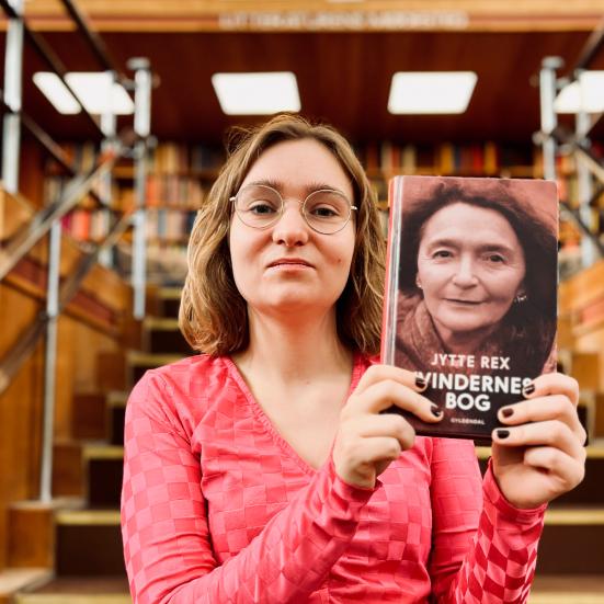 Litteraturformidler Amalie Pind stående med 'Kvindernes bog'