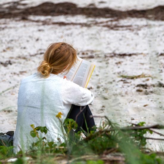 Pige på strand med bog