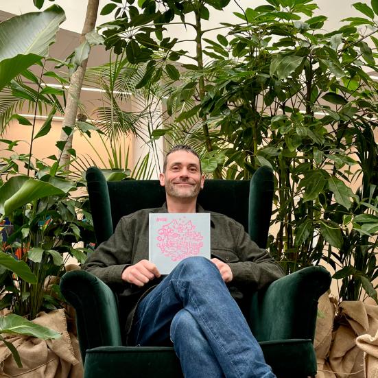 En sidende mand foran nogle planter viser bogen "Inger"