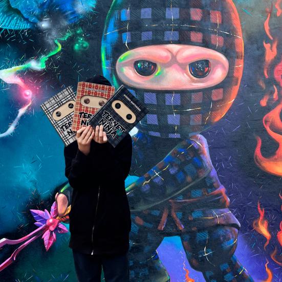 Gavlmaleri med ternet nonja og dreng der holder ternet ninja-bøger