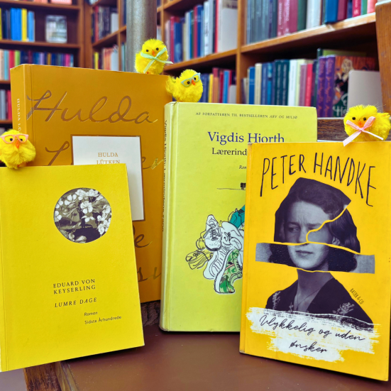 Gule bøger med påskekyllinger. i baggrunden bibliotekets hylder