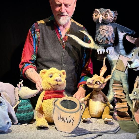 Skuespiller med dukkeudgaver af Peter Plys og hans venner.