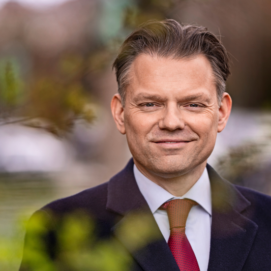 Portræt af borgmester Michael Vindfeldt der smiler. Tær på og ude i noget grøn natur. 