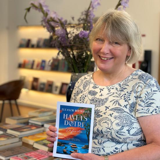 Bibliotekaren viser bogen foran bord med bøger og blomster