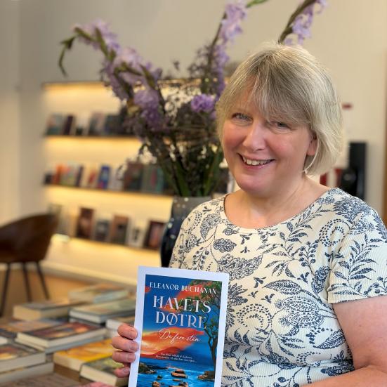 Bibliotekaren viser bogen foran bord med bøger og blomster