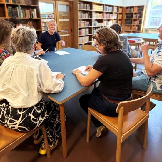 Gruppe af personer der sidder og snakker rundt om et bord