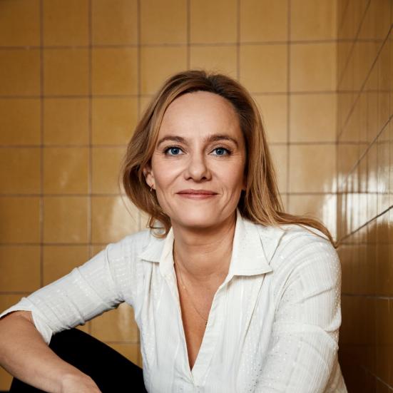 Forfatter Maren Uthaug siddende foran en baggrund af hvide kakler