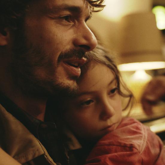 Stillbillede fra filmen med far og datter i omfavnelse.