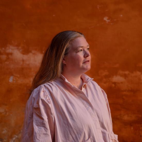 Forfatteren Amalie Laulund Trudsø i profil på baggrund af en rød mur.