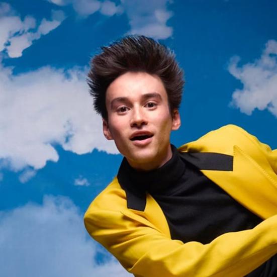 Billede af Jacob Collier iført gult jakkesæt på en baggrund af blå himmel.