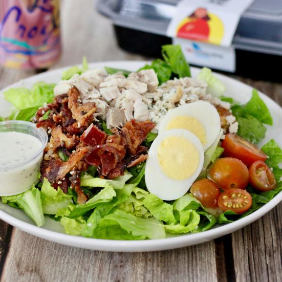 billede af tallerken med æg og bacon og tomat på bund af salat