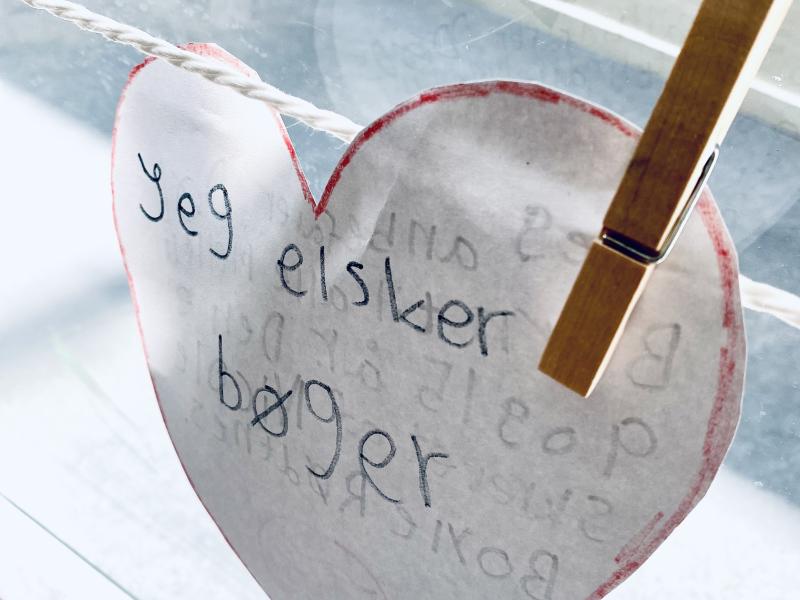 Udklippet hjerte med teksten Jeg elsker bøger, fastsat med klemme på en snor.