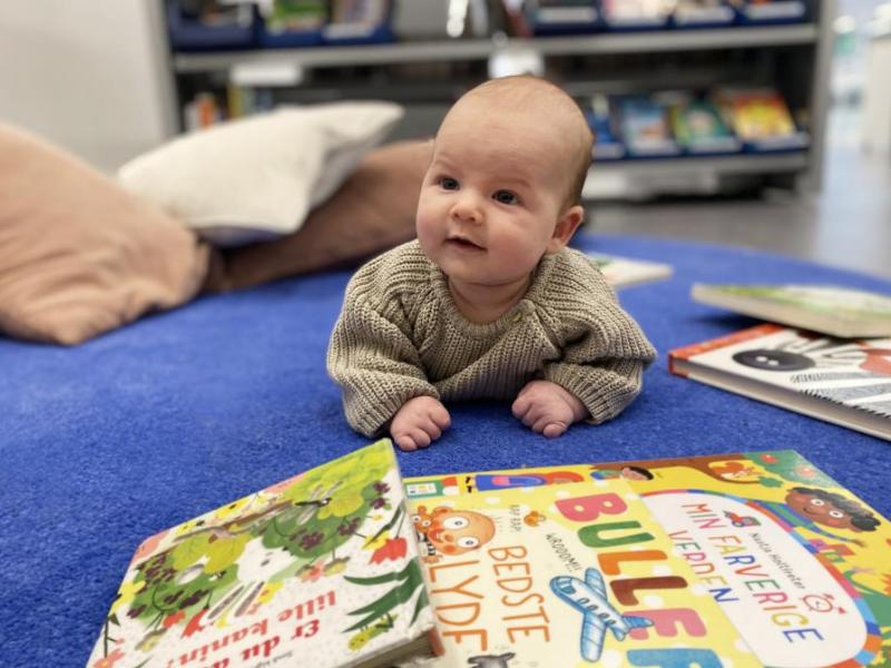 baby ligger på gulv med pegebøger