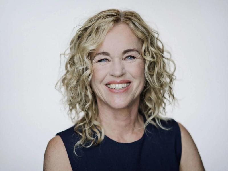 Smilende Anja C. Andersen på hvid baggrund.