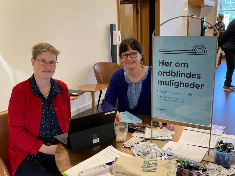 Billede af to kvindelige vejledere fra ordblindevejledningen siddende ved et bord på biblioteket