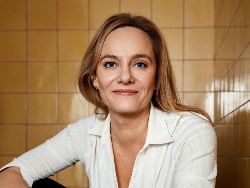 Forfatter Maren Uthaug siddende foran en baggrund af hvide kakler
