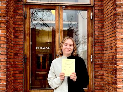 Litteraturformidler Amalie Pind med bogen Almanak foran bibliotekets indgang.