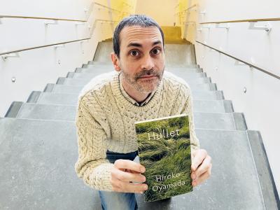 Billedet viser en mand på en trappe, og der holder bogen "Hullet" af Hiroko Oyamada