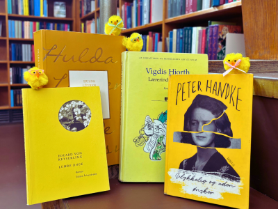 Gule bøger med påskekyllinger. i baggrunden bibliotekets hylder