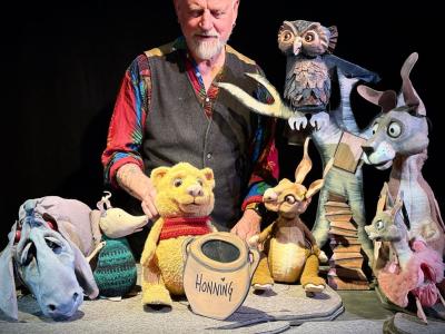 Skuespiller med dukkeudgaver af Peter Plys og hans venner.