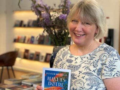 Bibliotekaren viser bogen foran bord med bøger og blomster