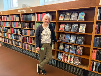 Bibliotekaren står foran reolerne med bibliotekets krimisamling