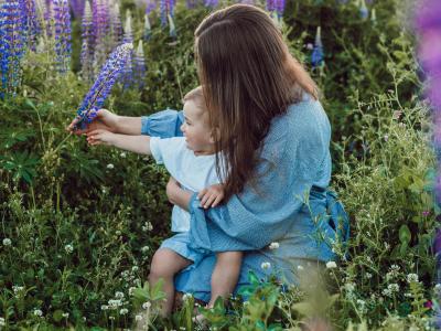 Mor og barn siddende i en blomstermark.
