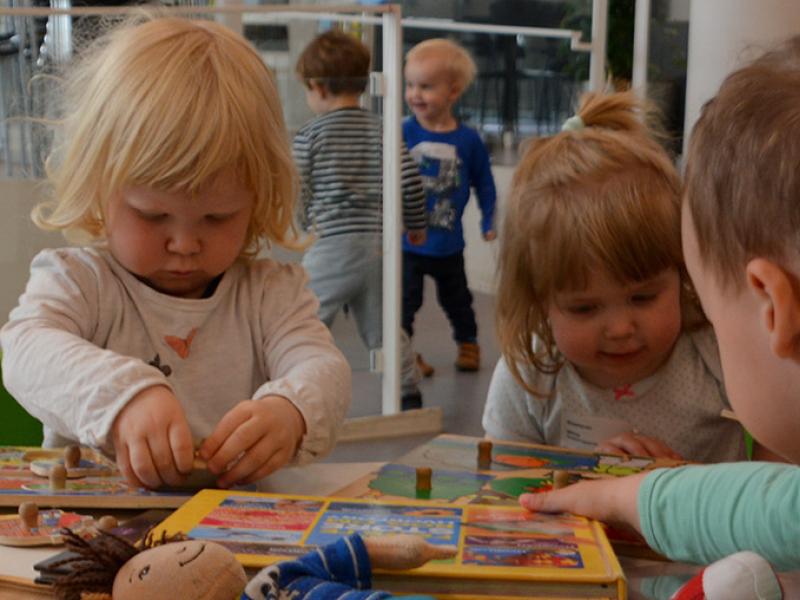 Små børn der sidder sammen med puslespil