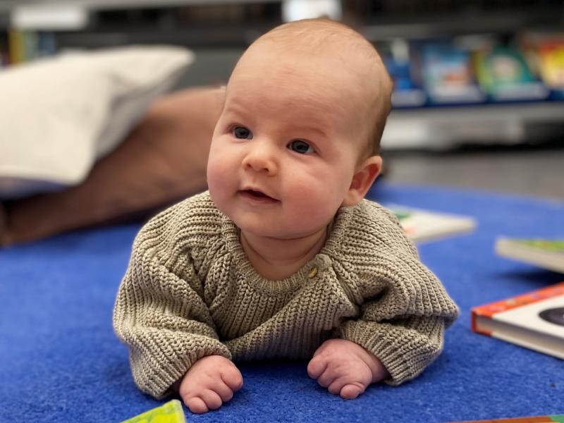 Baby liggende på pude med bøger