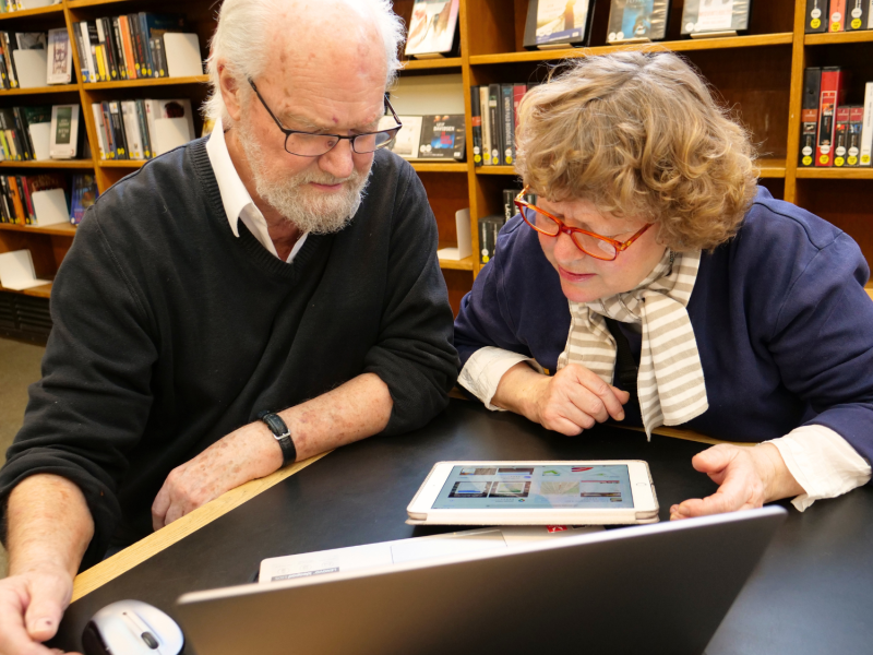 Mand og kvinde sidder i læringssituation ved computer og tablet