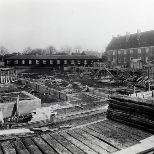 Byggepladsen, hvor den nye bygning så småt er undervejs. Bag fundamenterne ses biblioteksbarakken på Jernbanestien.