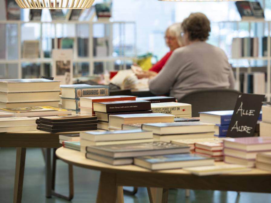 To inspiratorieborde med en masse bøger og to ældre kvinder i baggrunden.