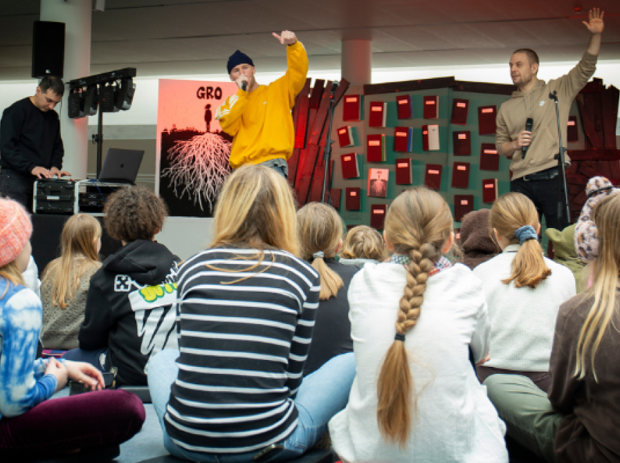 Tre rapper på en scene med børn foran.