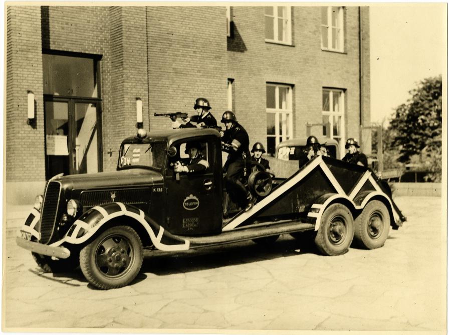 Billedet viser en vogn med politimænd foran Frederiksberg Hovedbibliotek i maj 1945