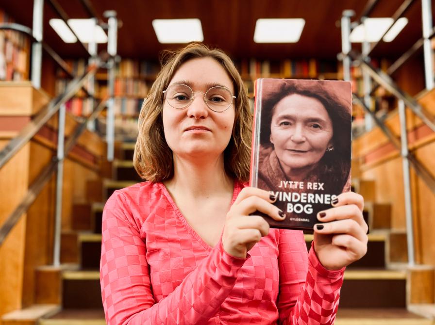 Litteraturformidler Amalie Pind stående med 'Kvindernes bog'