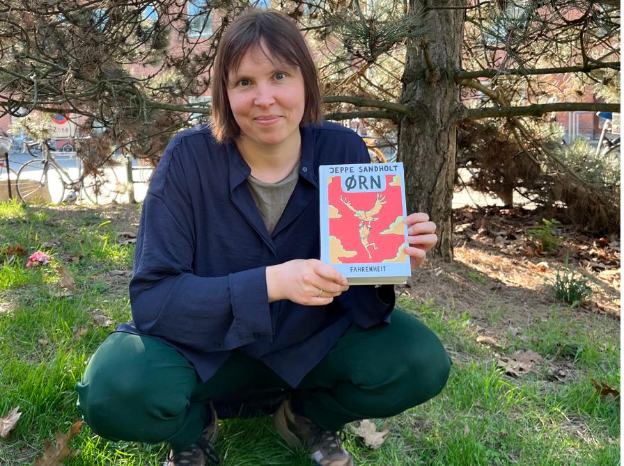 Bibliotekar holder bogen Ørn, I baggrunden et træ.