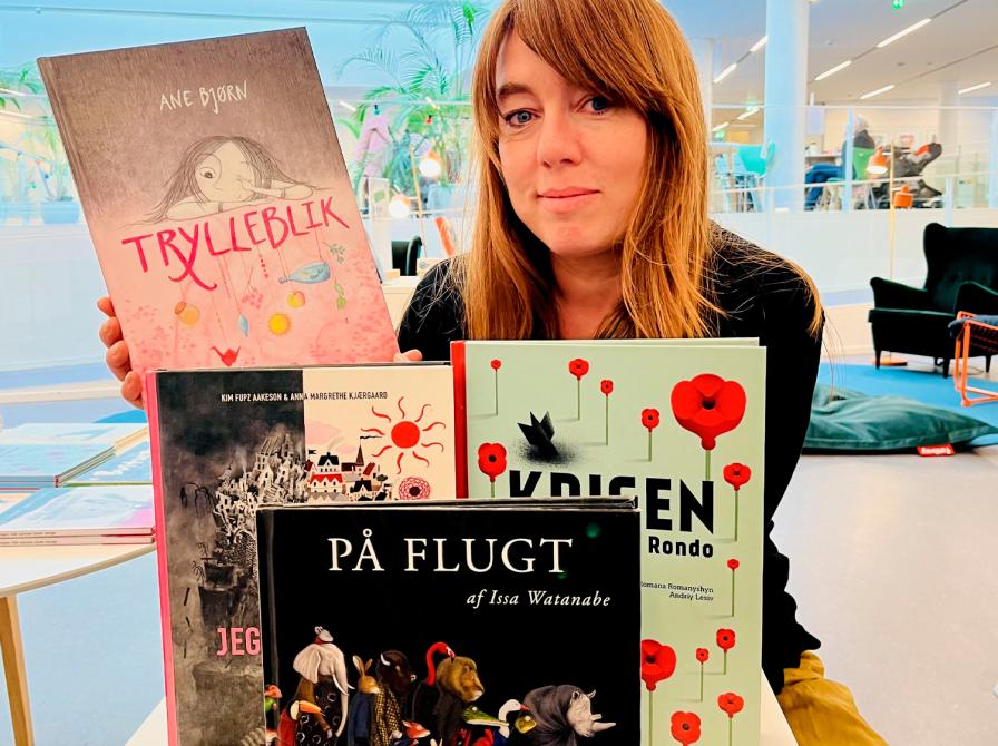 Kvindelig børnebogsformidler siddende med fire udvalgte bøger