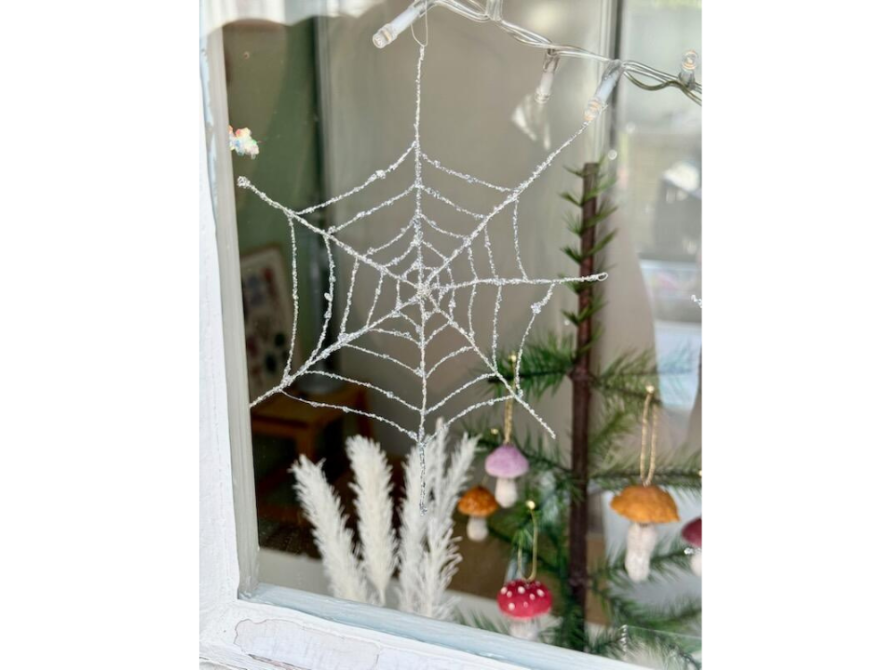 Glitrende spindelvæv ophængt i vindue