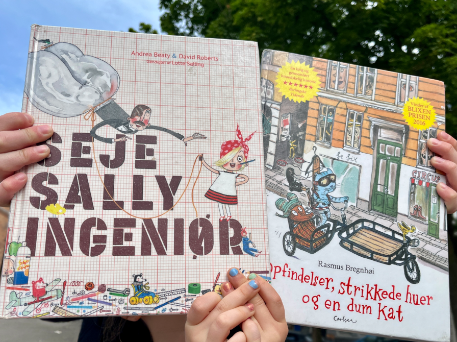 børnehænder holder 2 børnebøger: Seje Sally ingeniør + Opfindelser, strikkede huer og en dum kat.png