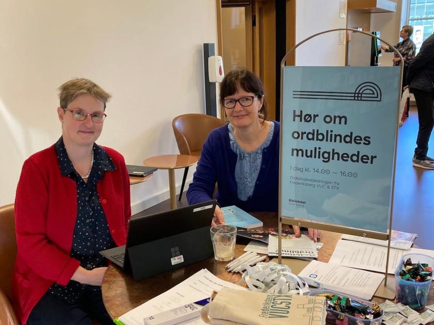 Billede af to kvindelige vejledere fra ordblindevejledningen siddende ved et bord på biblioteket