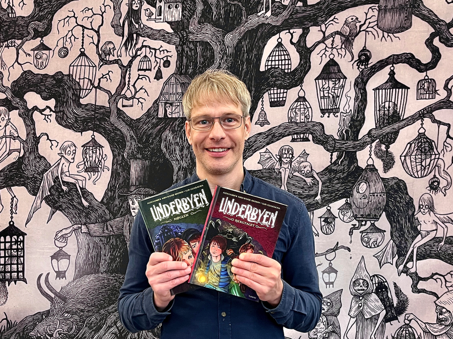 Bibliotekar holder bind 1 og bind 2 af tegneserien Underbyen 
