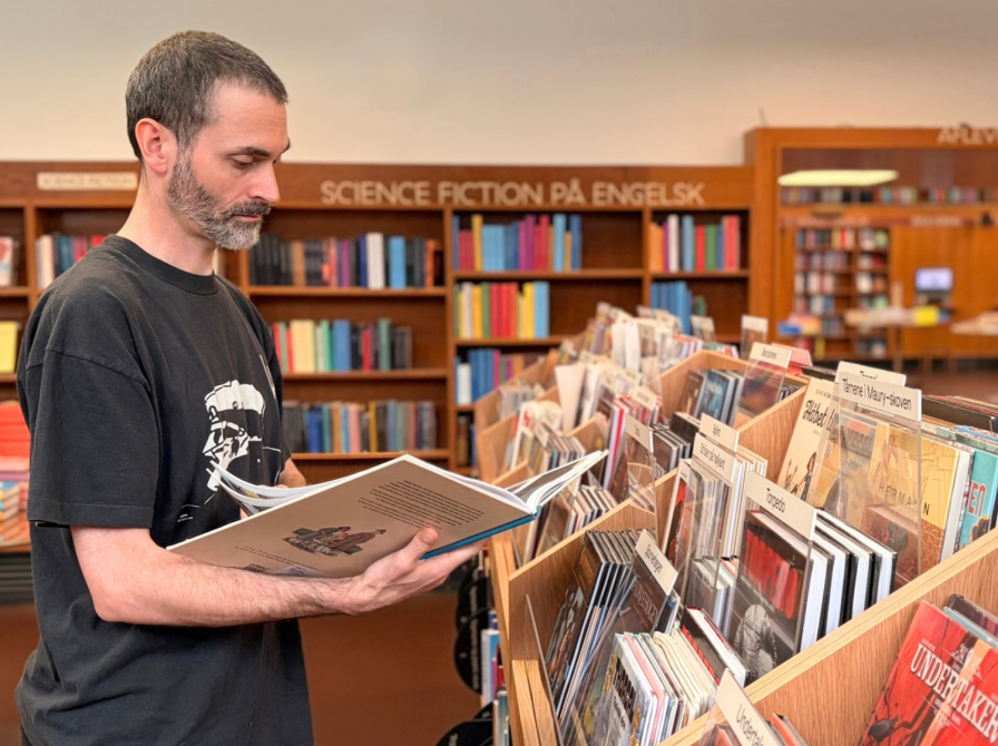 Bibliotekar ser på tegneserie ved nyt møbel i Nordsalen