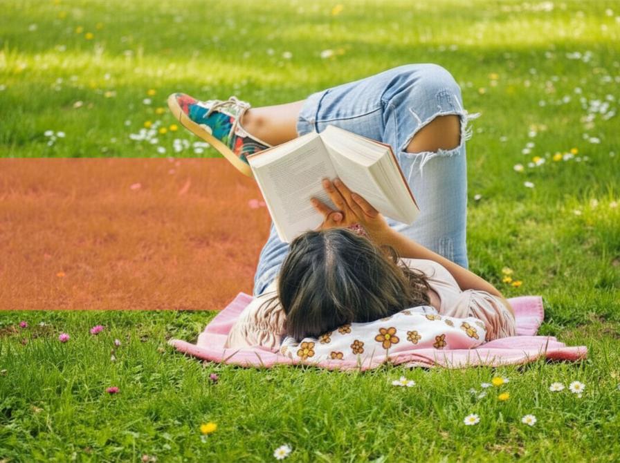 Læsesituation udendørs: Person slapper af i en park og læser en bog på en solrig græsplæne.