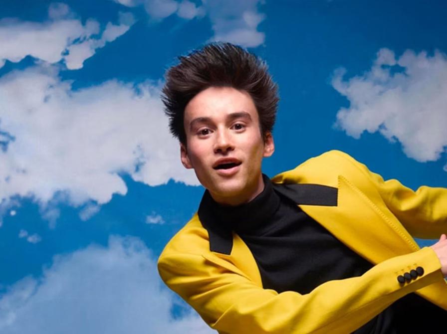 Billede af Jacob Collier iført gult jakkesæt på en baggrund af blå himmel.