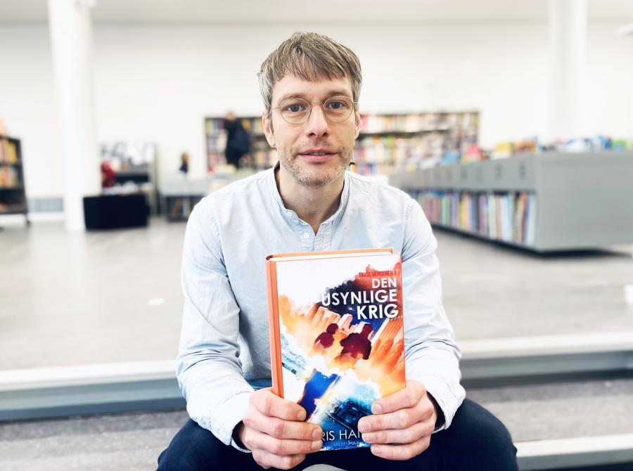 Bibliotekets børnebibliotekar Andreas med første bind i Boris Hansens science fiction-bogserie 'Tavse verdener'.